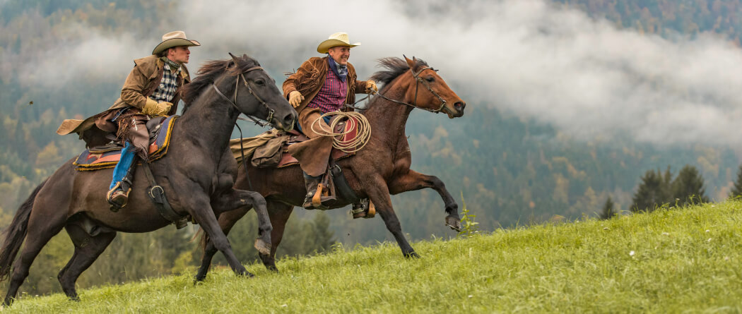 Two cowboys on running horses