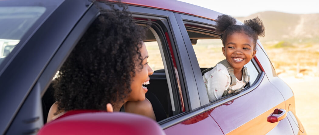 Mom and young girl leaning out of a car