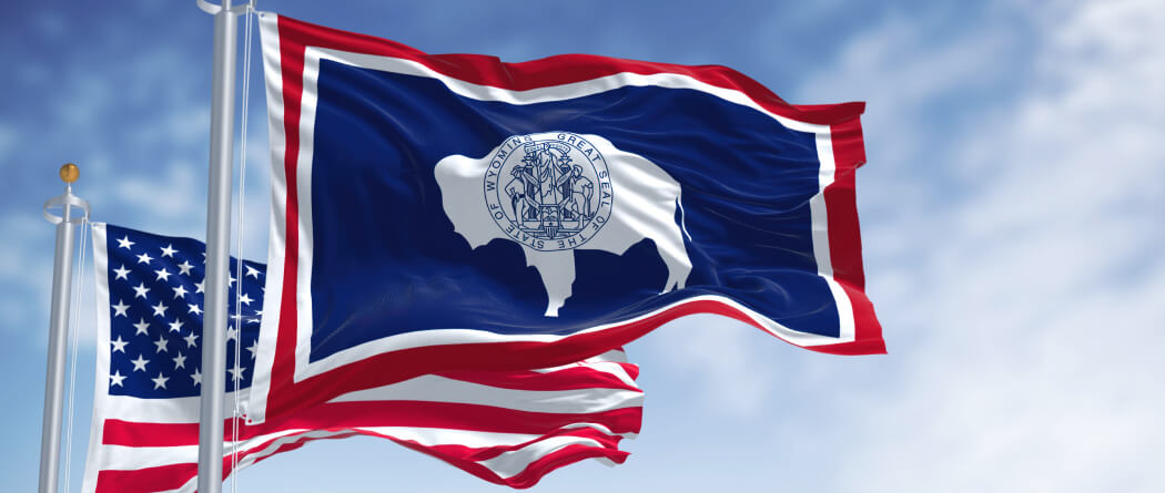 The Wyoming state flag and the American flag against a blue sky