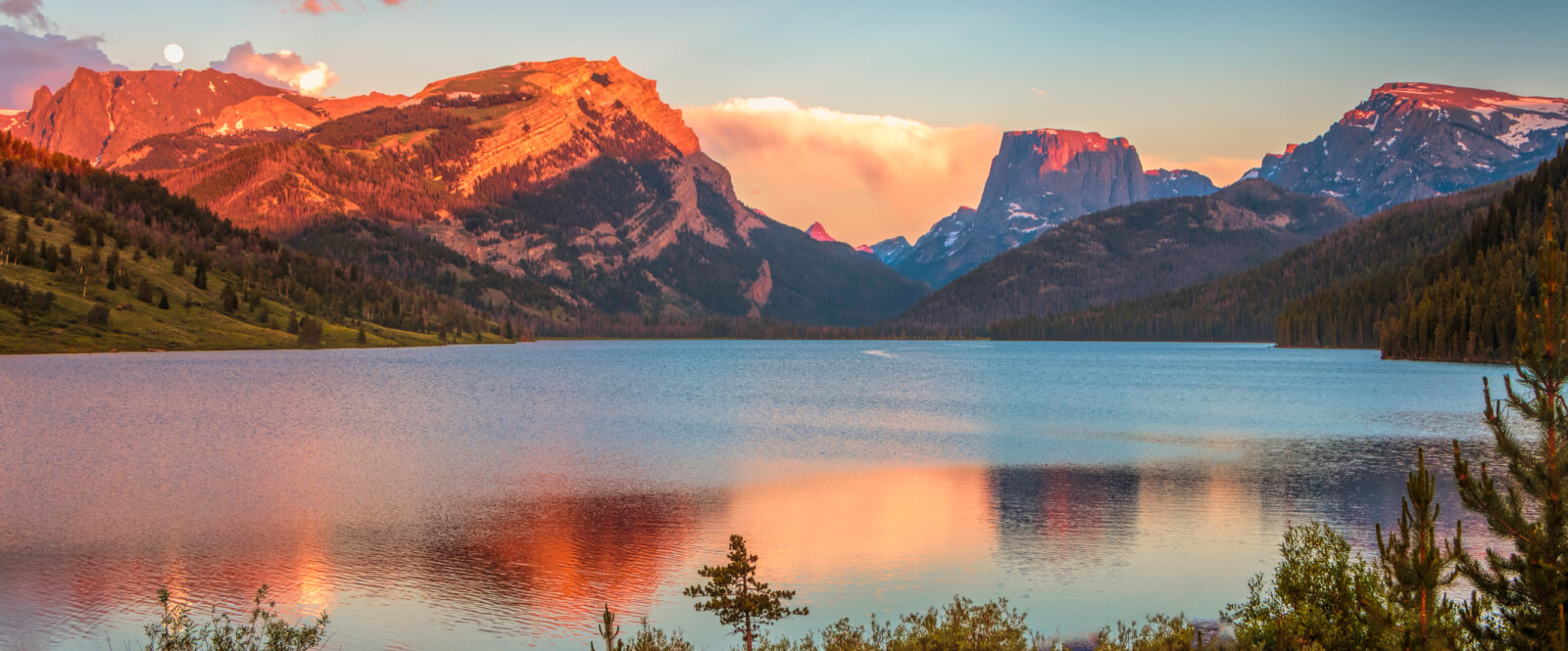 A landscape of a body of water below a mountain range